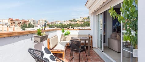 A terrace with outdoor furniture, a view of the city, and a potted plant.