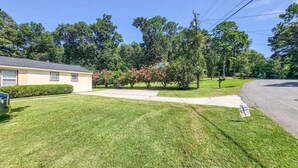 A residential property with a well-maintained lawn, a single-story house, and a driveway leading to a street. - 5-Bedroom, 3-Bathroom Cozy Home (Warner Robins)