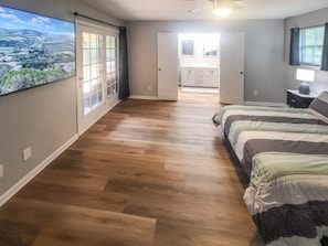Quarto com uma janela grande, uma cama e vista para uma cozinha.