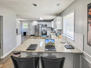 Cozinha moderna com bancadas de granito, eletrodomésticos de aço inoxidável e iluminação pendente.