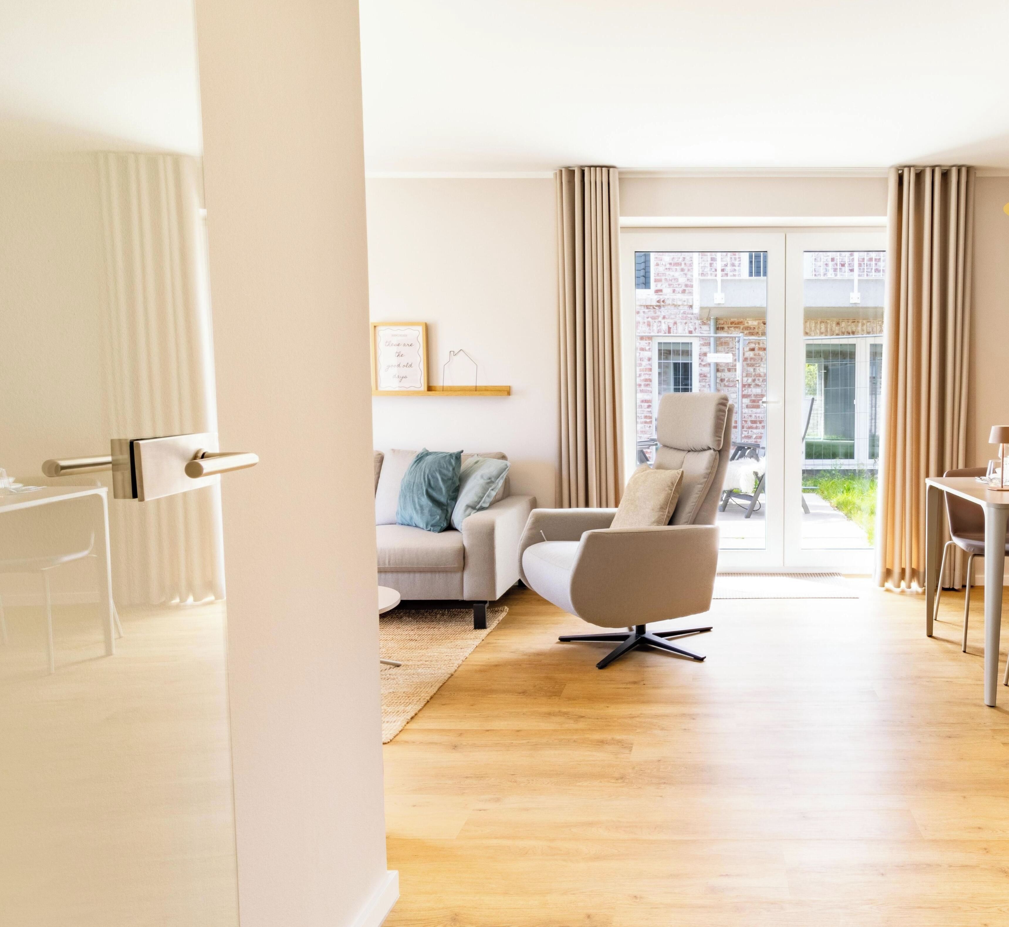 Ein modernes Wohnzimmer mit Sofa, Sessel und Esstisch.