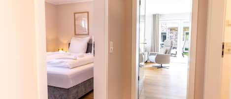 Una habitación de hotel con cama, mesita de noche, lámpara y vistas al exterior.