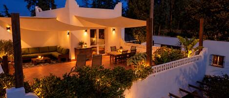 A modern outdoor patio area with a dining set, seating, and ambient lighting.