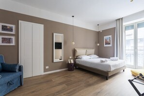 Ein modernes Schlafzimmer mit Bett, Sofa, Kleiderschrank und Spiegel.