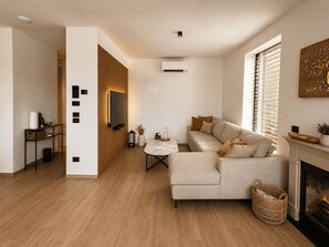 Ein modernes Wohnzimmer mit einer Couch, einem Kamin und einem Fernseher.