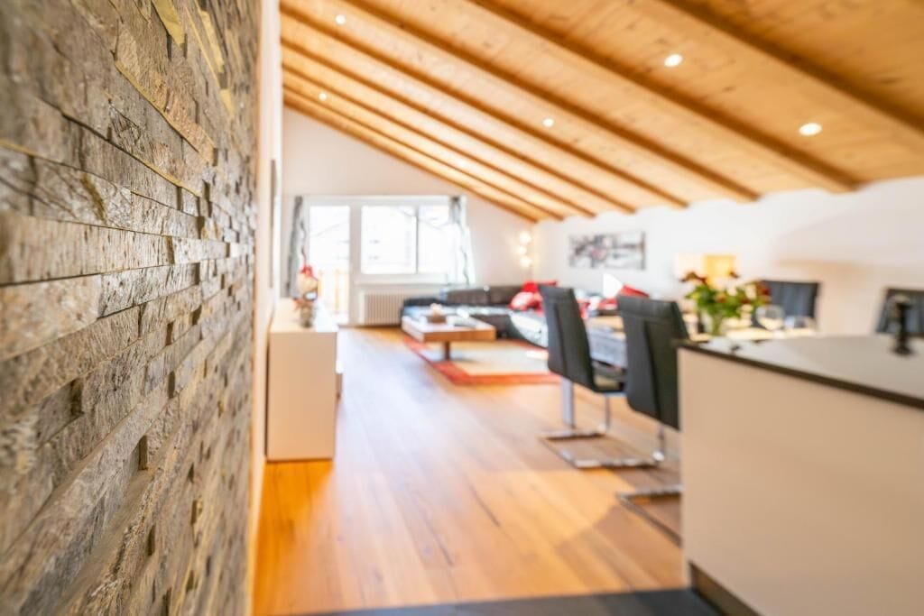 Ein modernes Interieur mit Holzbalkendecke, Essbereich und Küche.