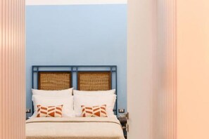 Ein Bett mit Kopfteil, Kissen und Decke in einem Zimmer mit blauen Wänden.