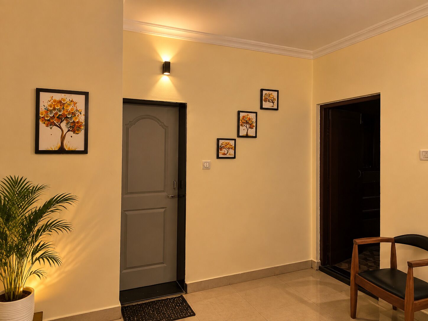 A hallway with a door, a wall-mounted light, and a potted plant.