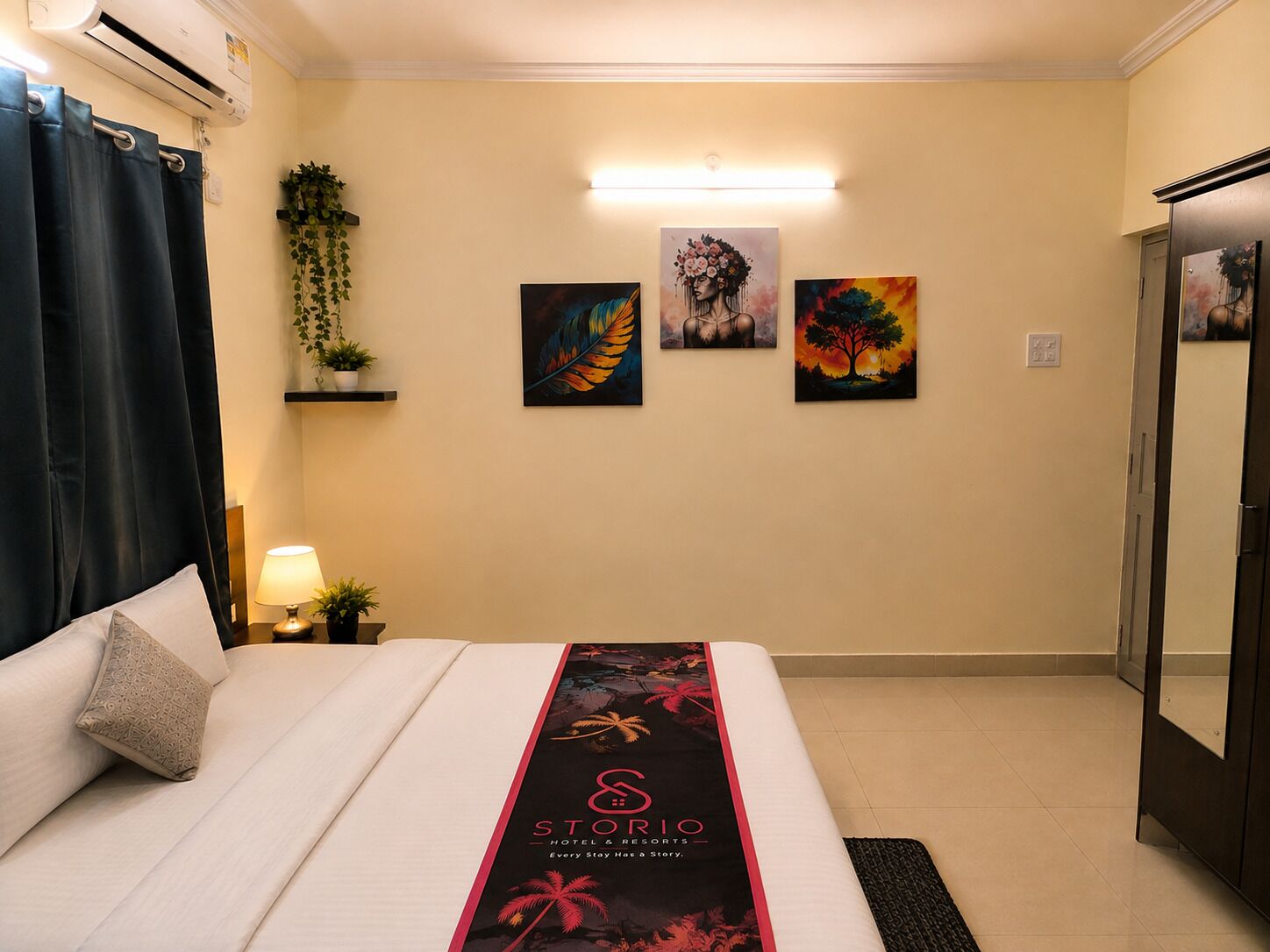 Una habitación de hotel con cama, mesita de noche con lámpara, aire acondicionado instalado en la pared y una obra de arte en la pared.