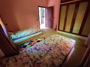 Een kamer met twee bedden, een kleurrijk tapijt en een houten deur.