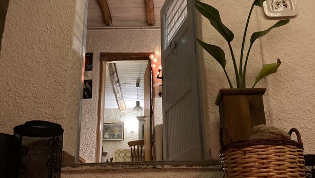 A staircase leading to a room with a door, a potted plant, and a wall-mounted electrical outlet.