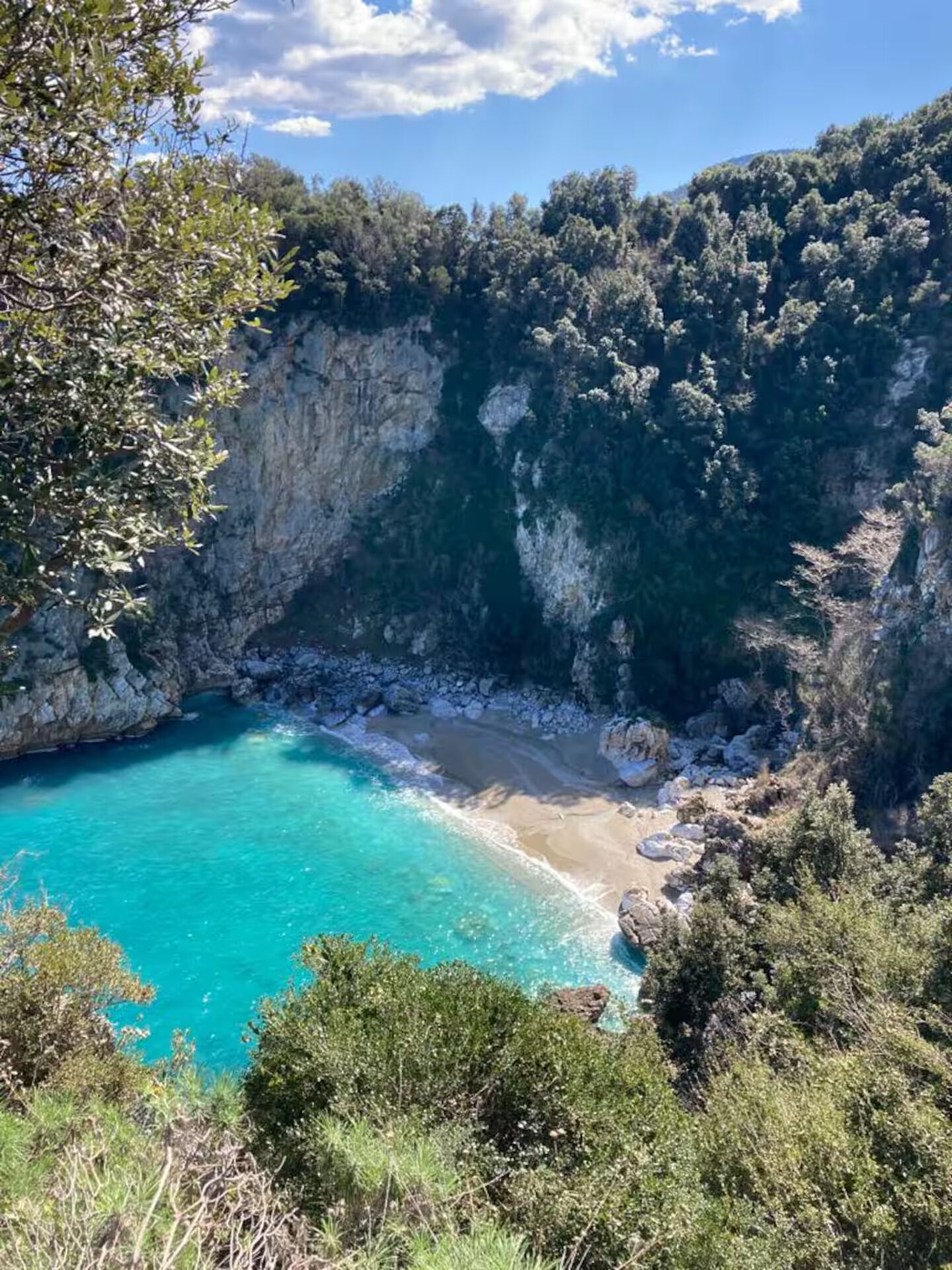 Un paysage côtier caractérisé par une mer bleue et limpide, des falaises rocheuses et une végétation luxuriante.