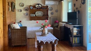 A cozy living room with a sofa, a table with a vase of flowers, a bookshelf, and a television.