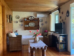 A cozy living room with a sofa, a table with a vase of flowers, a bookshelf, and a television.