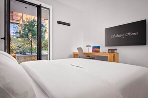 A hotel room with a bed, a desk, a chair, a TV, and a view of the outdoors. - NEW: Casa Sabina - Residence Corte Carden 2 (Bardolino)