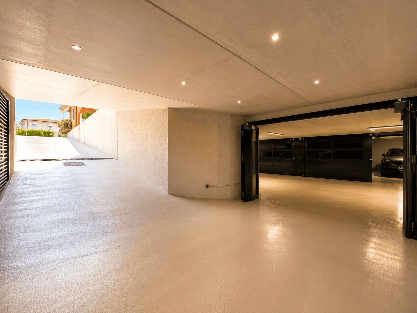 Un parking souterrain moderne, avec un sol en béton propre et une voiture garée à l’intérieur.