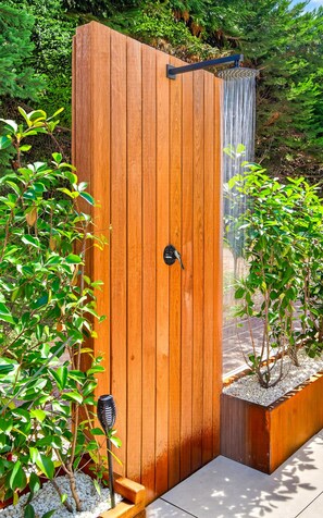 Une porte en bois agrémentée d’un élément décoratif à base d’eau, le tout entouré de verdure.