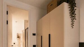 Un couloir avec une armoire, une plante et un panier posé sur le dessus.