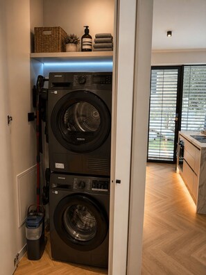 A laundry room with two Samsung washing machines, a basket, a bottle of shampoo, and towels. - NEW: Casa Sabina - Residence Corte Carden 2 (Bardolino)