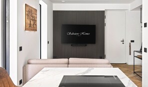 A modern living room with a flat-screen TV mounted on a wall, a sofa, and a coffee table. - NEW: Casa Sabina - Residence Corte Carden 2 (Bardolino)