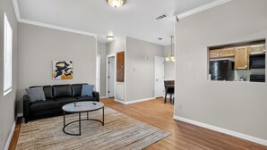 A modern living room with a black sofa, a round coffee table, and a patterned rug. - Comfortable Living in Saddlebrook (Lumberton)