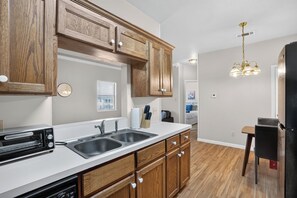 Una cocina con gabinetes de madera, un lavamanos doble, un tostador y un refrigerador.