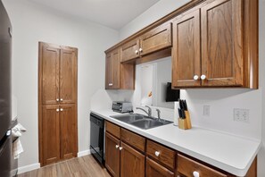 A kitchen with wooden cabinets, a dishwasher, a double sink, and a knife block. - Comfortable Living in Saddlebrook (Lumberton)
