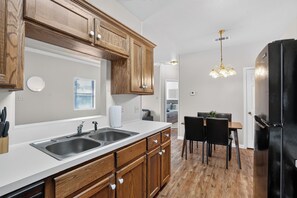 A modern kitchen with wooden cabinets, a double sink, and a black refrigerator.