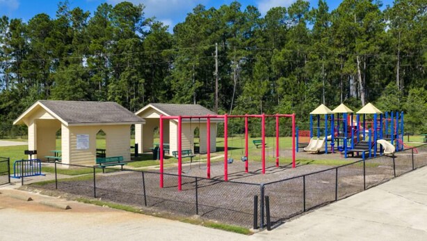A playground with a red and blue play structure, a small shelter, and a picnic table. - Saddlebrook: Comfortable Furnished Apartment (Lumberton)