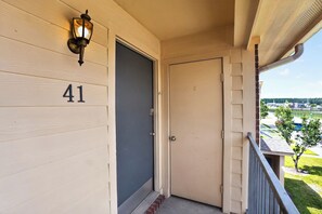 Une porte en bois portant le numéro 41, un porche avec une rambarde en métal et une vue sur un quartier résidentiel.