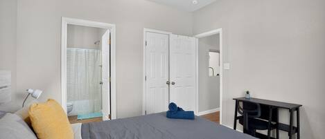 A bedroom with a bed, a desk, and a ceiling fan.