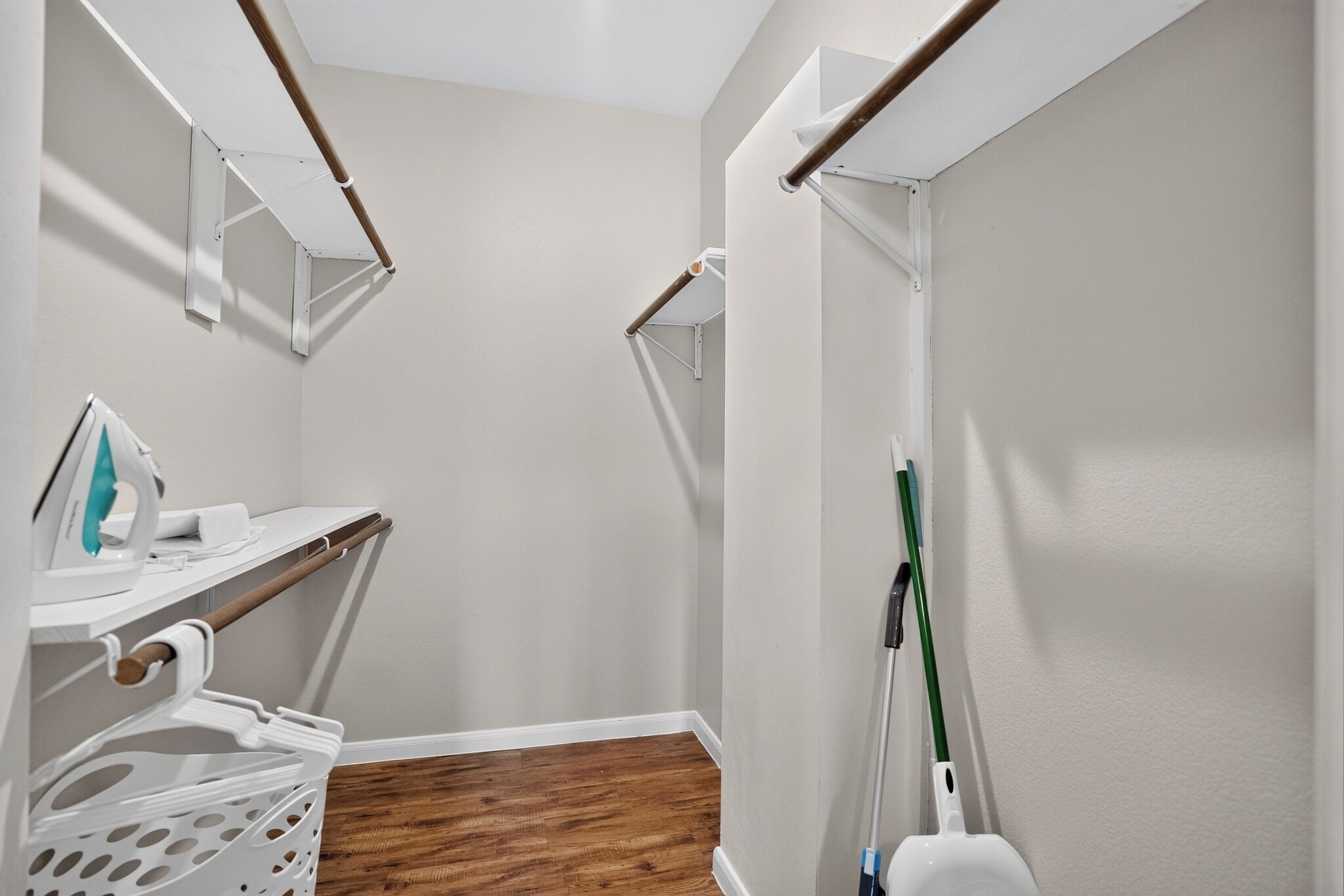 A clean, modern bathroom with a wooden floor, a white sink, and a green mop leaning against the wall.