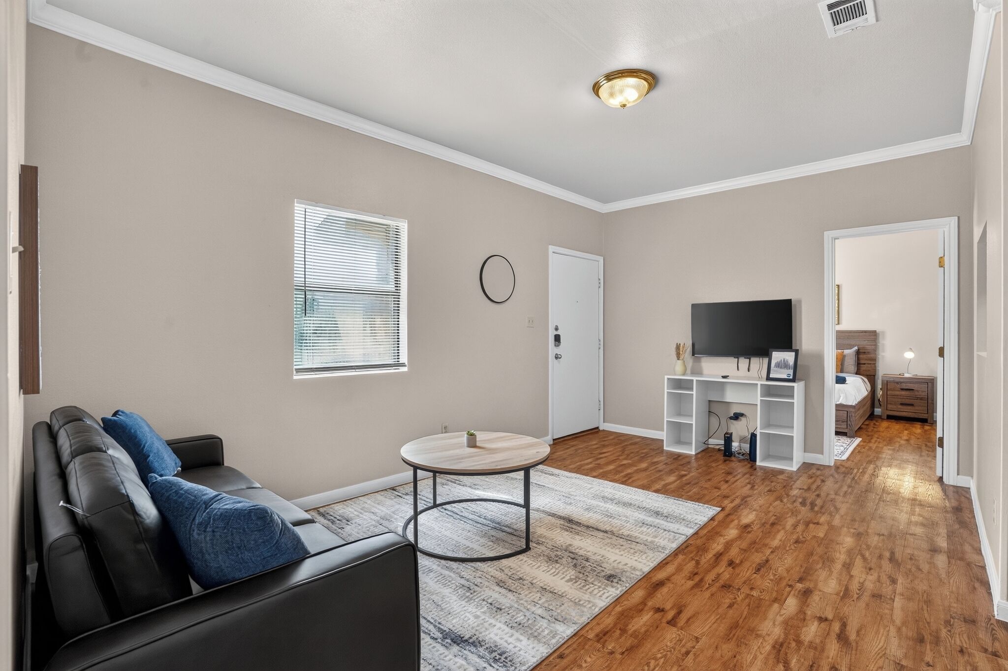 Un salon avec un canapé, une table basse, un téléviseur et un plancher en bois.