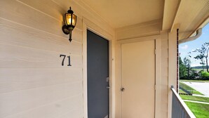 En bygningseingang med nummer 71 på væggen, en dør og en lampe over døren.