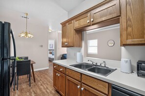 Una cocina moderna con armarios de madera, un lavamanos doble y un comedor con mesa y sillas.