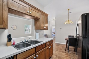A modern kitchen with wooden cabinets, a double sink, and a black refrigerator.