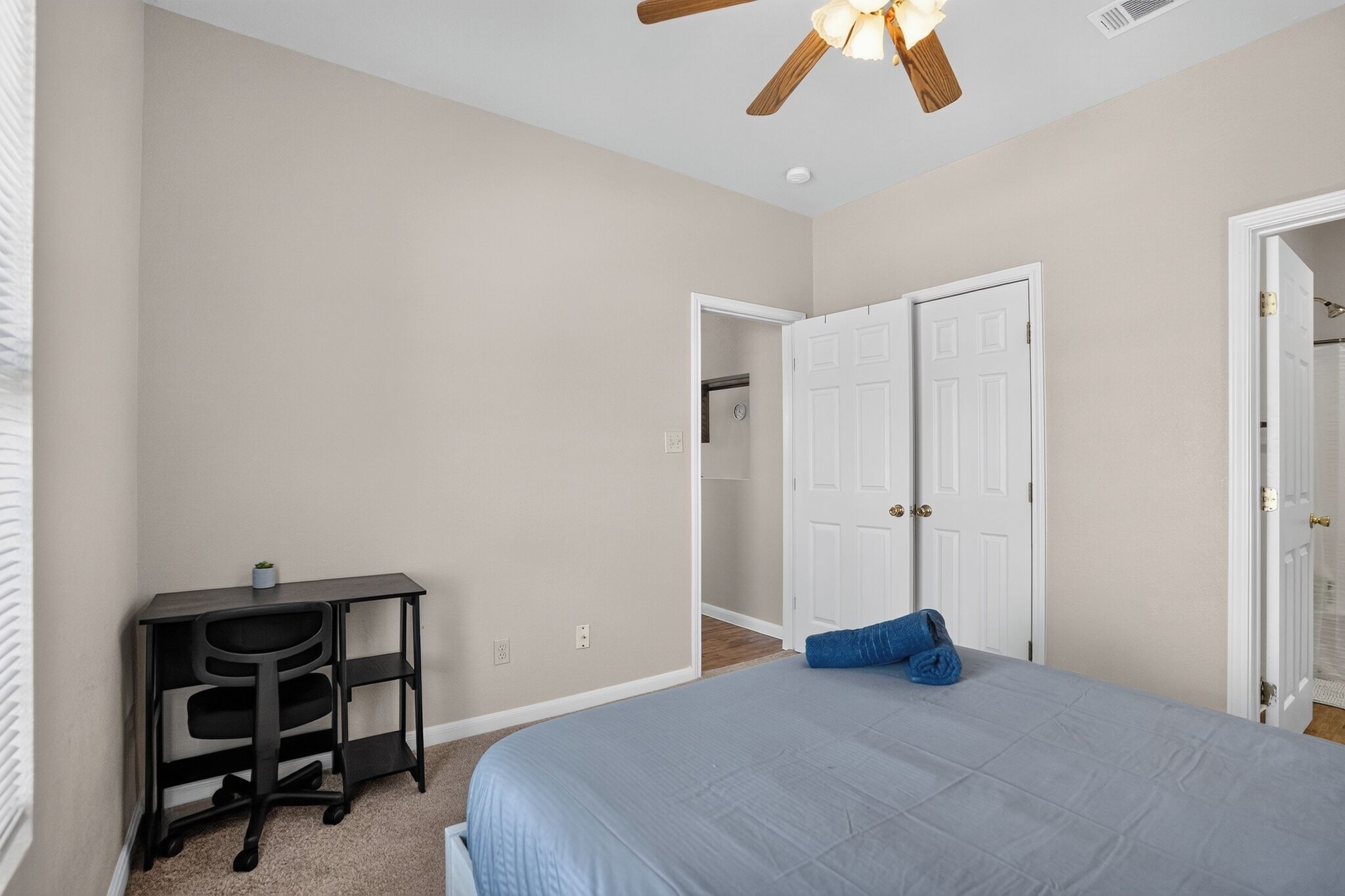 A bedroom with a bed, a desk, and a closet.