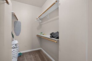 Ein kleines, schmales Badezimmer mit Dusche, einem Regal mit Handtuch und einem an der Wand hängenden Bügeleisen.