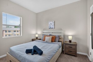 Ein Schlafzimmer mit einem Bett, zwei Nachttischen, einem Fenster und einem Wandbild.