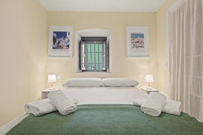 Een hotelkamer met een bed, twee nachtkastjes, een raam en twee ingelijste foto's aan de muur.