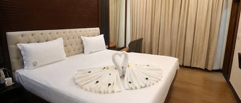 Una habitación de hotel con una cama grande, un cabecero de madera, una mesita de noche con lámpara y una silla.