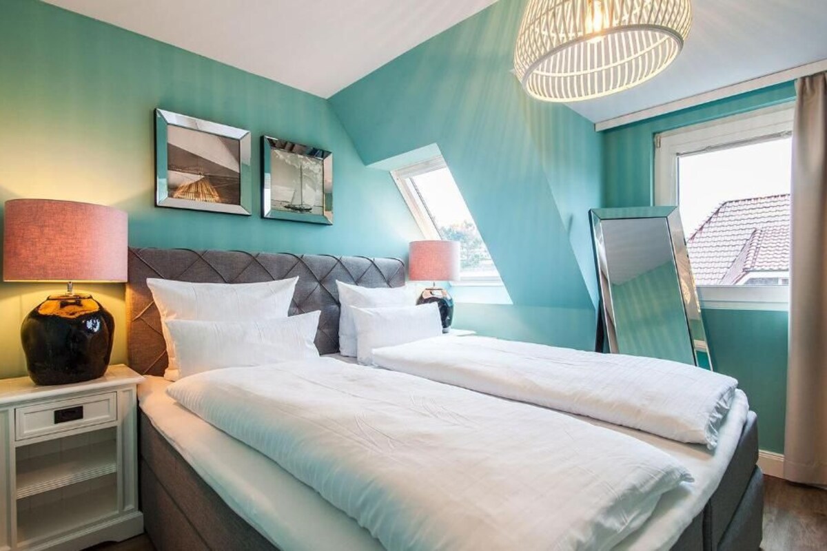 A bedroom with a bed, nightstands, a lamp, and a window.