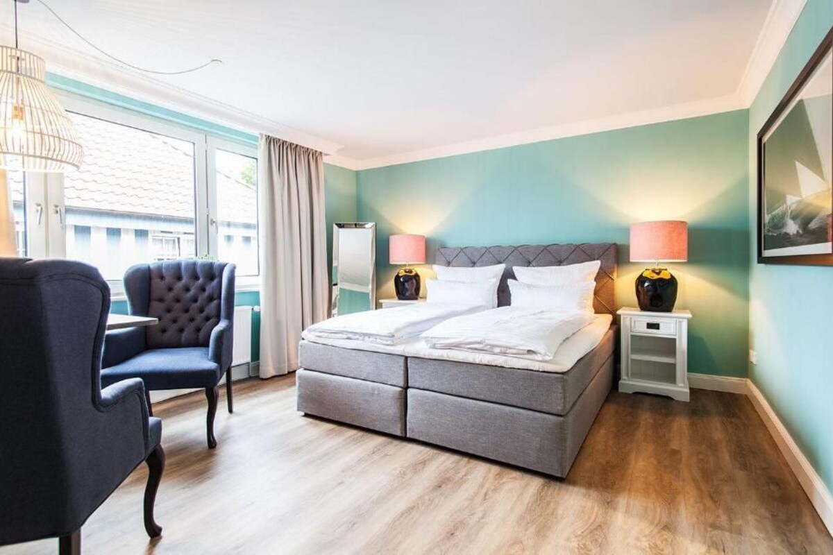 A bedroom with a bed, bedside tables, a chair, and a window.