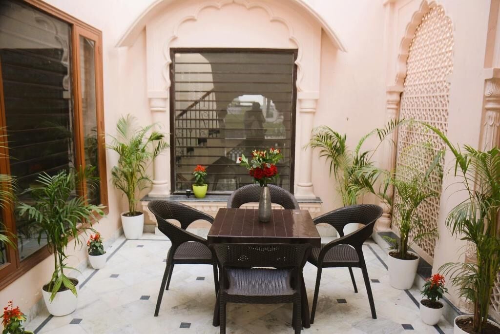 An outdoor seating area with a table and chairs, surrounded by potted plants.