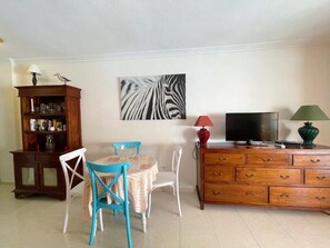 A living room with a wooden cabinet, a television, a red lamp, and a zebra print artwork on the wall. - Edificio Don Antonio (Arona)
