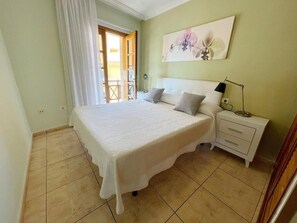 Un dormitorio con cama, mesita de noche y un cuadro en la pared.