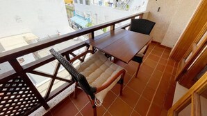 A balcony with a table and two chairs, a view of the city, and a tiled floor. - Edificio Don Antonio (Arona)