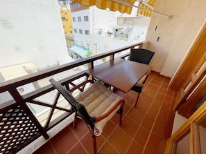 Ein Balkon mit Tisch und zwei Stühlen, Blick auf die Stadt und ein Fliesenboden.