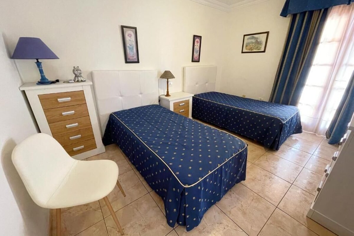 Ein Schlafzimmer mit zwei Betten, einem Sessel, einem Schminktisch und einem Nachttisch.