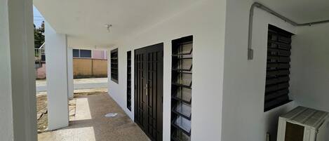 A corridor with multiple black-framed windows and a white air conditioning unit.